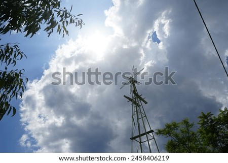 A weather vane is placed in the garden in August in Pefki. A wind vane, weather vane, or weathercock is an instrument used for showing the direction of the wind. Pefkos or Pefki, Rhodes Island Royalty-Free Stock Photo #2458406219