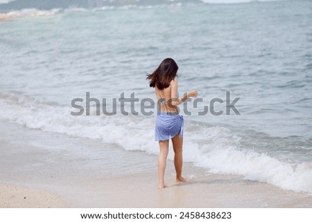 Full body back of Asian woman with bikini look enjoy and walking on a sunny beach with blue sea and fresh sky background. Concept of holidays and travel. Picture looking alone. Summer holiday season.