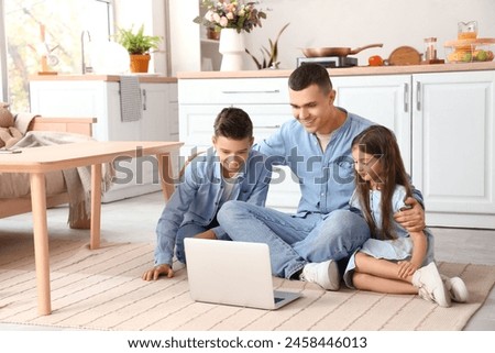 Little children with their father watching cartoons on laptop at home