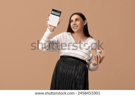 Pregnant young woman with calculator and piggy bank on beige background