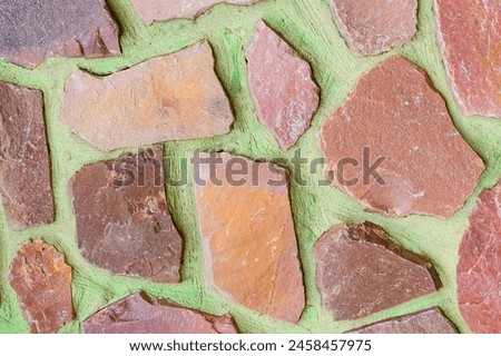 It is photo of colorful stones on green background. Its close up of multicolored stone wall of building. It is photo of the mosaic tile floor. It's view of wall texture.