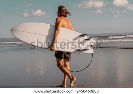 a European man carrying a white surfboard walks calmly on the beach. the perfect photo for summer