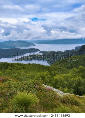 A panoramic view of the Norwegian landscape, showcasing the vast expanse of the North Sea, dotted with islands and adorned with a sky filled with summer clouds