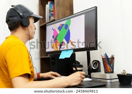 A man in a yellow shirt is working on a computer monitor. He is wearing headphones and he is focused on his work. The monitor displays a colorful image of a rocket