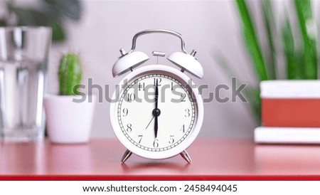 Classic white clock on a table. The clock hand points at 6:00. close up photo