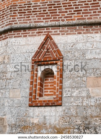 An ancient loophole in the fortress wall walled up with bricks Royalty-Free Stock Photo #2458530827