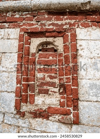 An ancient loophole in the fortress wall walled up with bricks Royalty-Free Stock Photo #2458530829