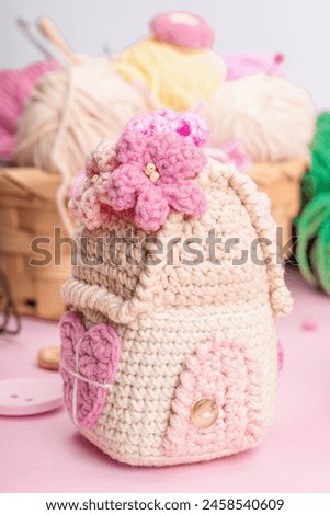 Handmade spring decor concept. Creative crocheting, house figurines, traditional flowers and stuff. Festive greeting card, gentle pastel pink background, close up