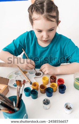 Cute little girl mixing paints on palette. Selected Focus. High quality photo