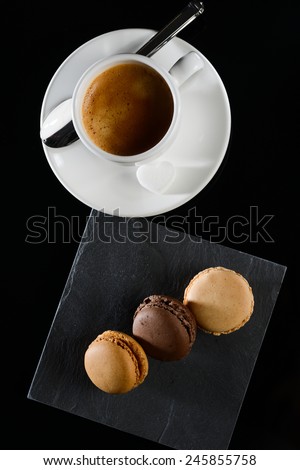 three macaroon on a slate with espresso coffee on background