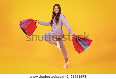 Stylish teen girl with shopping sale bags. Run and jump. Kid holding purchases.