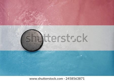 old vintage hockey puck is on the ice with national flag of luxembourg .