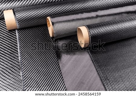 Rolls with various real woven carbon fiber enforcement raw material cloth. composite material automotive and car tuning  industry and high tech background. 