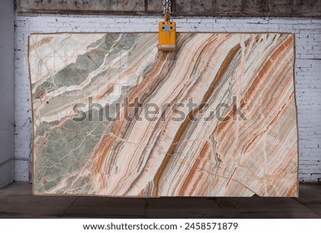 Picture of a marble slab on a hanger, shot in natural light, a cut of decorative marble in a warehouse, a large piece of marble. High resolution photo. Onyx Rainbow