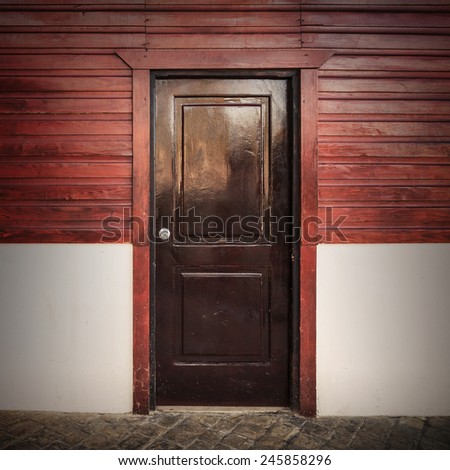 Old wooden door in white and red rural house facade