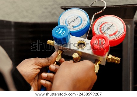 Pressure measurement device able to detect damaged expansion valve, freon not circulating properly and other issues. Close up of capable specialist using manifold meter to recondition hvac system Royalty-Free Stock Photo #2458599287