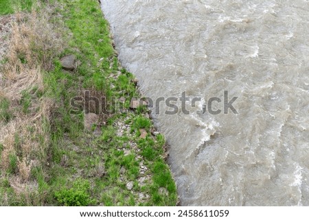 glancing down over the bridge to river bank and flowing water