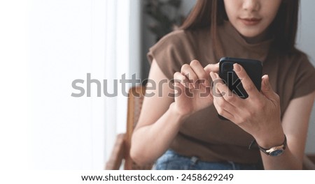 Young asian woman in casual wear using mobile phone for online shopping or digital banking via mobile app at home. 30s woman checking her social media on smartphone at coffee shop, close up