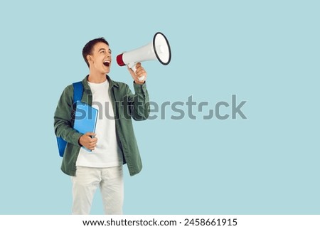 Young male student with megaphone, businessman proclaiming, addressing public, audience, calling, speaking loud in communication, protest or advertisement, attention for commercial promotion Royalty-Free Stock Photo #2458661915