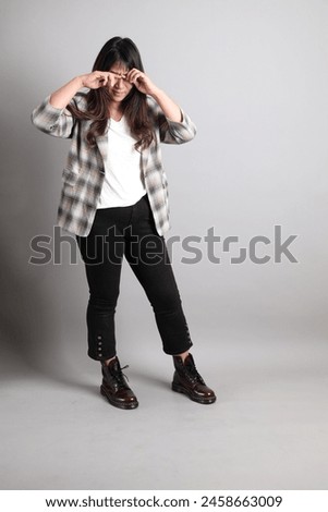 the adult Asian woman standing on the grey background, with gesture of disappointed, crying.