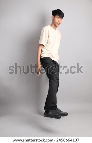 The Young South Asian teen with the casual clothes standing on the gray background