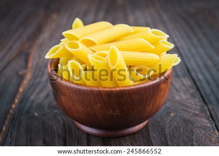 Raw pasta in wooden bowl on wood background - process old dark style picture