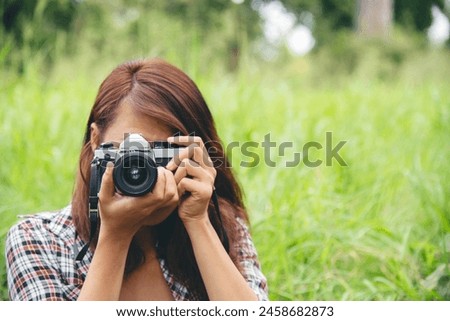 Close up hands Asian Women look at dslr digital camera vintage film style take a photo. Professional female photographer look at picture outdoor. Young woman hands shooting photo in green nature park