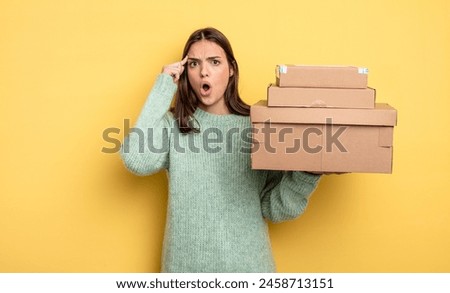 pretty woman looking surprised, realizing a new thought, idea or concept packages boxes concept
