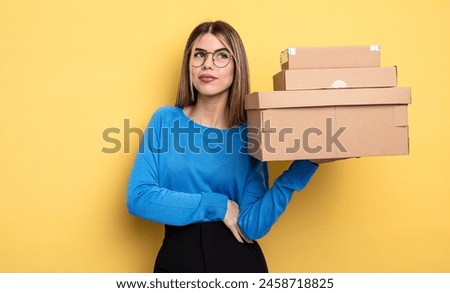 pretty woman shrugging, feeling confused and uncertain packages boxes concept