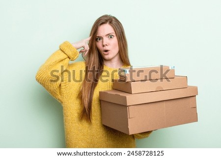 red hair woman looking surprised, realizing a new thought, idea or concept. packages boxes concept