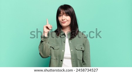 plus size pretty woman feeling like a genius holding finger proudly up in the air after realizing a great idea, saying eureka Royalty-Free Stock Photo #2458734527