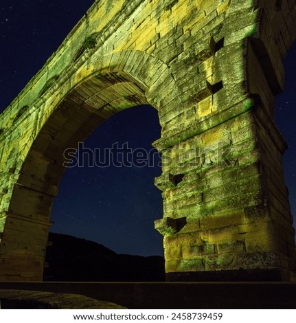 The Pont du Gard is an ancient Roman aqueduct, that is depicted  on five euro note. Bridge lit up at night time. Summer 2022. Royalty-Free Stock Photo #2458739459