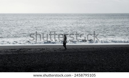Lonely tourist on a beach. Photographer walks on the sand. Inspiration, freedom, travel, photography. Northern lands, cold, windbreaker.
