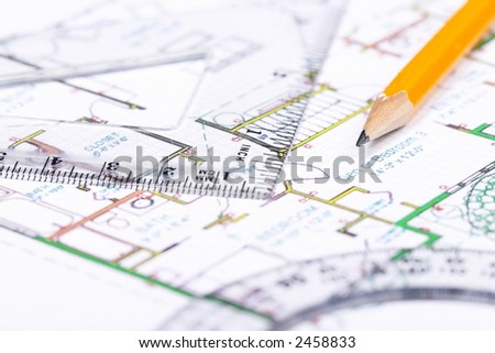 A protractor, pencil and a setsquare on top of a floor plan. Focus on pencil's tip.