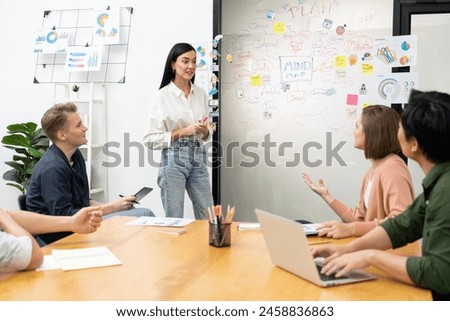 Young beautiful leader presents marketing strategy while expert investor and project manager lecturing to analyze business performance at start up business meeting. Multiethnic group. Immaculate. Royalty-Free Stock Photo #2458836863