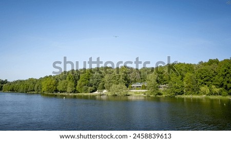 The valley of three ponds in Katowice. Restaurants on the lake shore. Airplane against the background of a clear blue sky. Poland