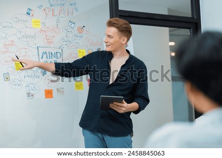 Professional male leader presents start up project by using mind map, colorful sticky notes and business statistic graph with confident while investor listening at business meeting. Immaculate. Royalty-Free Stock Photo #2458845063