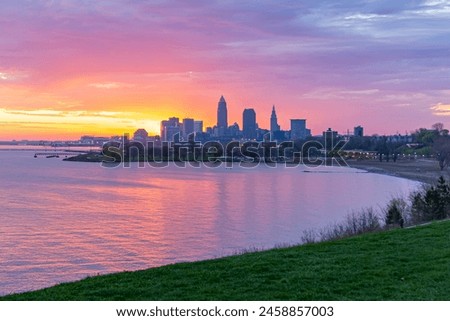 Downtown skyline silhouette behind bay with pink and yellow sunrise