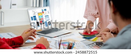 Cropped image of interior designer team presents color by using color swatches while laptop displayed UI and UX designs for mobiles app and website. Creative design and business concept. Variegated.