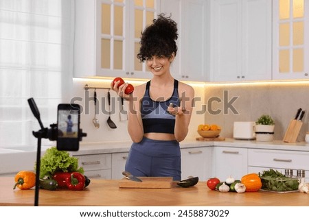 Smiling food blogger explaining something while recording video in kitchen Royalty-Free Stock Photo #2458873029