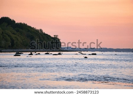 Sunset, illuminated sea. Sandy beach in the foreground. Light waves. Poel island on the Baltic Sea. Nature photo from the coast