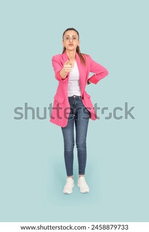 Warning threaten someone, full body view young brunette angry 20s woman warning threaten someone. Wear pink formal jacket and jeans pointing finger to camera. Yelling shouting outraged pissed woman. Royalty-Free Stock Photo #2458879733