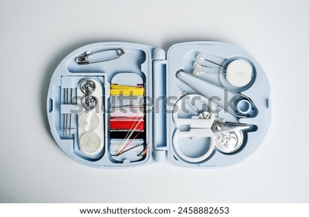Compact travel small sized tailoring or stitching tools equipment in plastic blue container storage. Object photography isolated on white background.