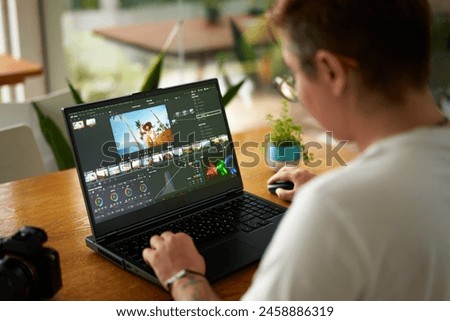 Professional video colorist adjusts footage colors on laptop in bright office. Creative industry editor works on film grading, enhances visual appeal. Expert uses software for post-production.