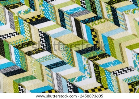 A quilt with a green and white pattern of chevrons. The quilt is made up of many different pieces of fabric, and the colors are bright and cheerful. The quilt has a playful and whimsical feel to it