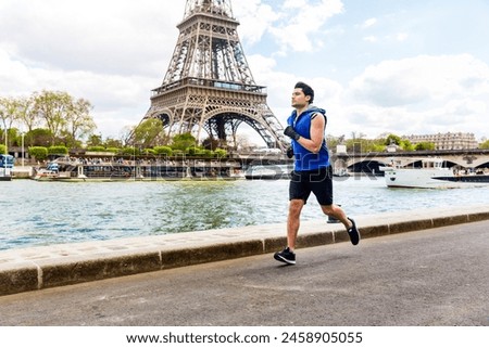 Man training and doing fitness exercises along the Seine river in Paris with Eiffel tower on background - Multiracial young man enjoying sport on a sunny day