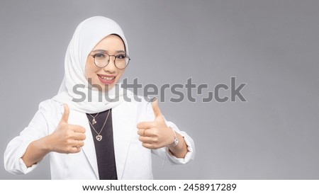 Portrait of Muslim woman in office attire and wearing a hijab. Corporate  or business people concept. Isolated on grey background. 16:9 ratio with copyspace on one side of the banner Royalty-Free Stock Photo #2458917289