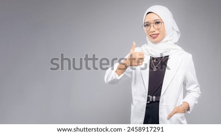 Portrait of Muslim woman in office attire and wearing a hijab. Corporate  or business people concept. Isolated on grey background. 16:9 ratio with copyspace on one side of the banner Royalty-Free Stock Photo #2458917291