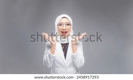 Portrait of Muslim woman in office attire and wearing a hijab. Corporate  or business people concept. Isolated on grey background. 16:9 ratio with copyspace on one side of the banner Royalty-Free Stock Photo #2458917293