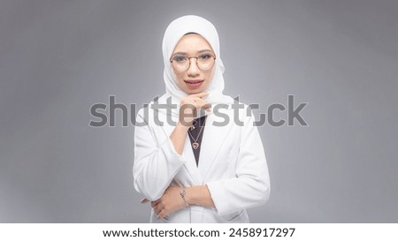 Portrait of Muslim woman in office attire and wearing a hijab. Corporate  or business people concept. Isolated on grey background. 16:9 ratio with copyspace on one side of the banner Royalty-Free Stock Photo #2458917297